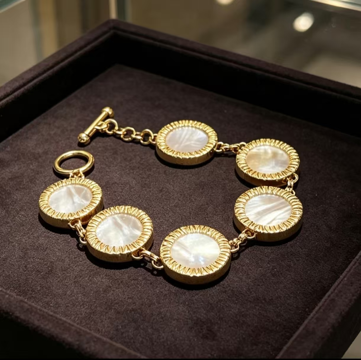 Overhead view of five mother-of-pearl discs linked in a gold-tone bracelet