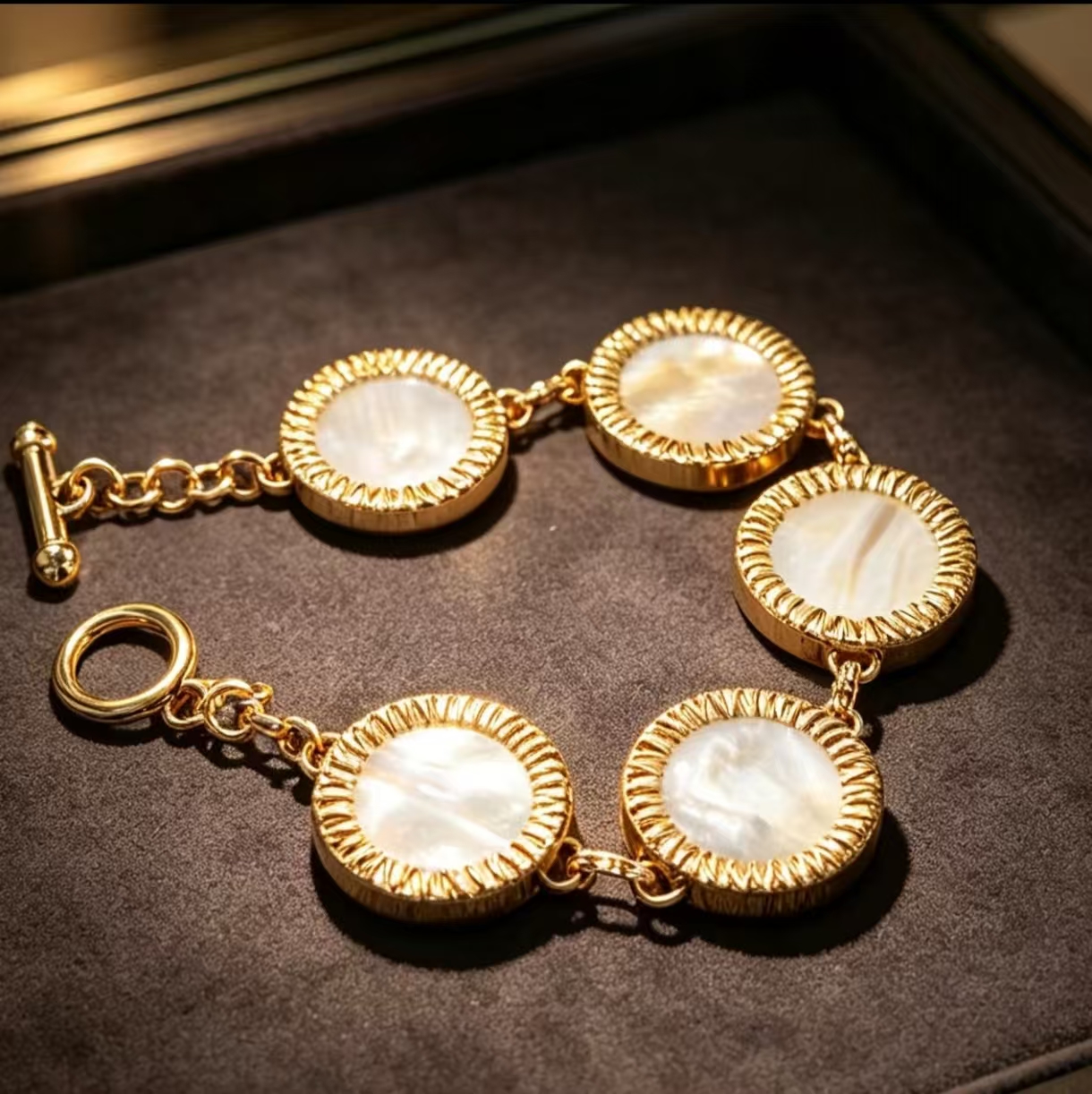 Five round mother-of-pearl discs linked in a gold-tone bracelet