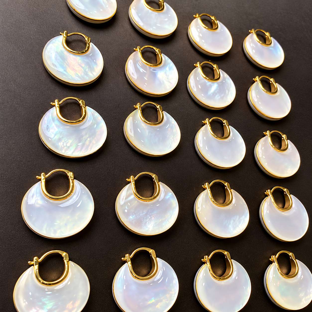 Close view of several mother-of-pearl disc earrings with gold-tone rims