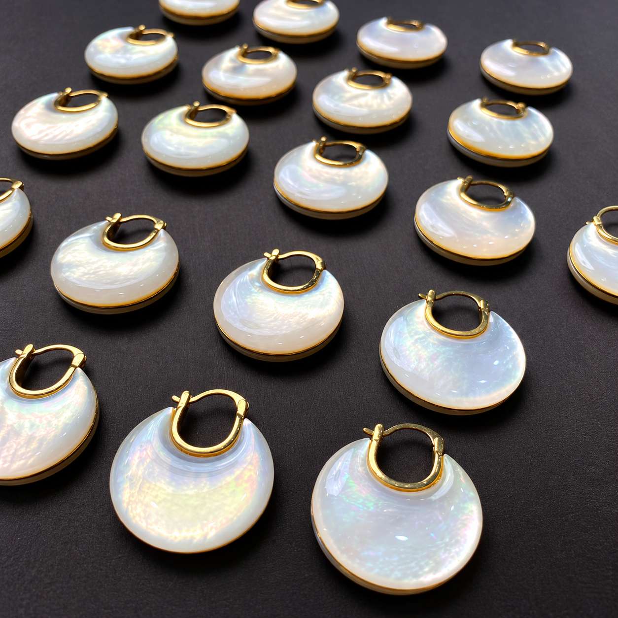 A group of mother-of-pearl disc earrings showing natural variations in the shell