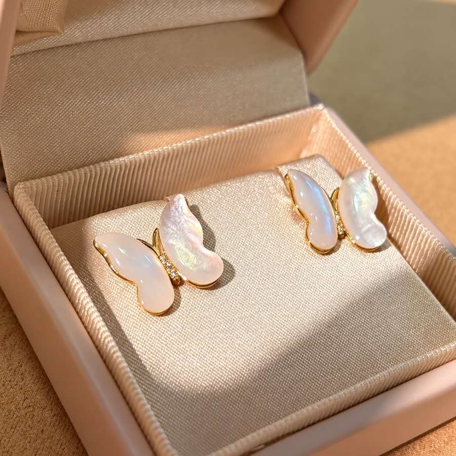 Butterfly-shaped mother-of-pearl earrings with gold-tone settings in a jewellery box